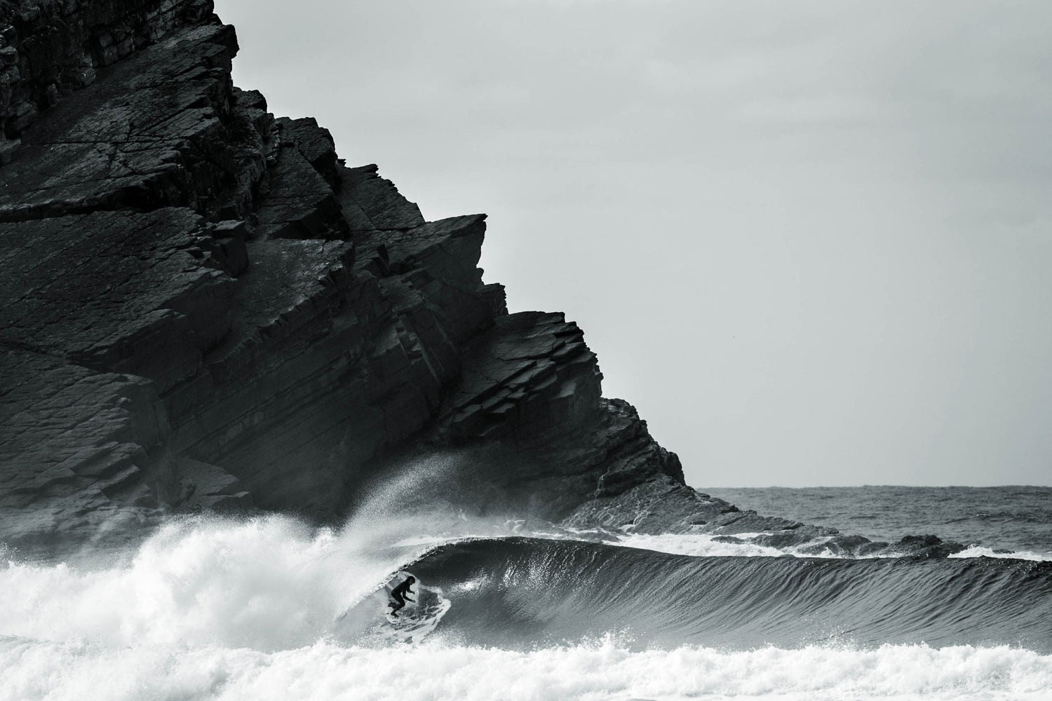 Surfer paddling into a wave representing the origins of surfing and heʻe nalu