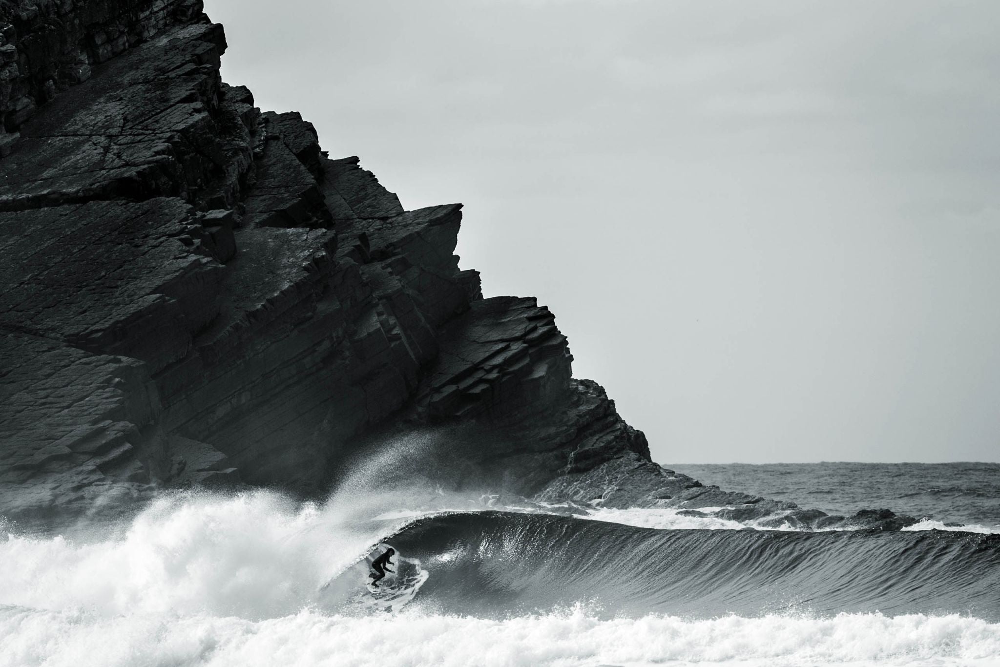 Surfer paddling into a wave representing the origins of surfing and heʻe nalu